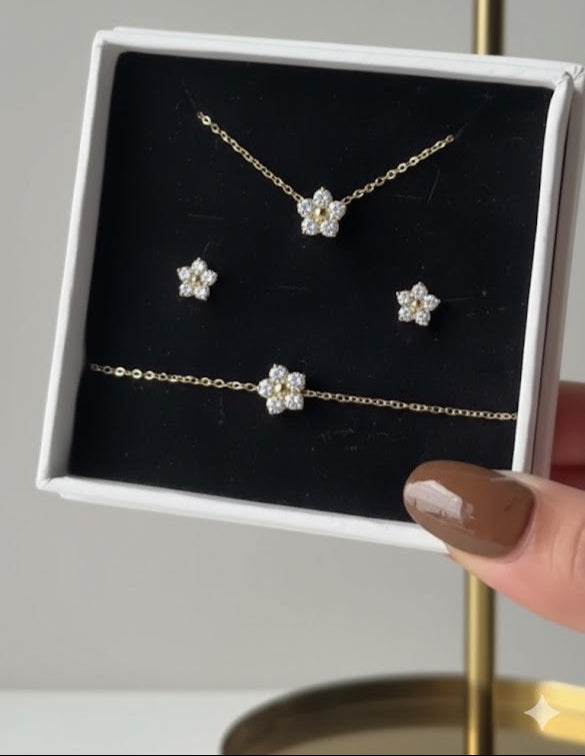 Jewelry set with necklace, bracelet, and earrings on a display card held by a hand.