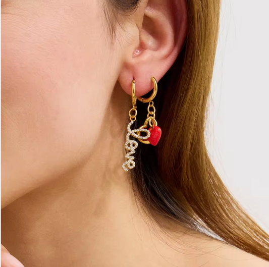 Gold hoop earrings with charms worn by a person on a white background