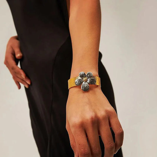 PVD 18K gold plated dual tone flower bracelet. Elegant floral design, water resistant stainless steel. Perfect for adding sophisticated charm.