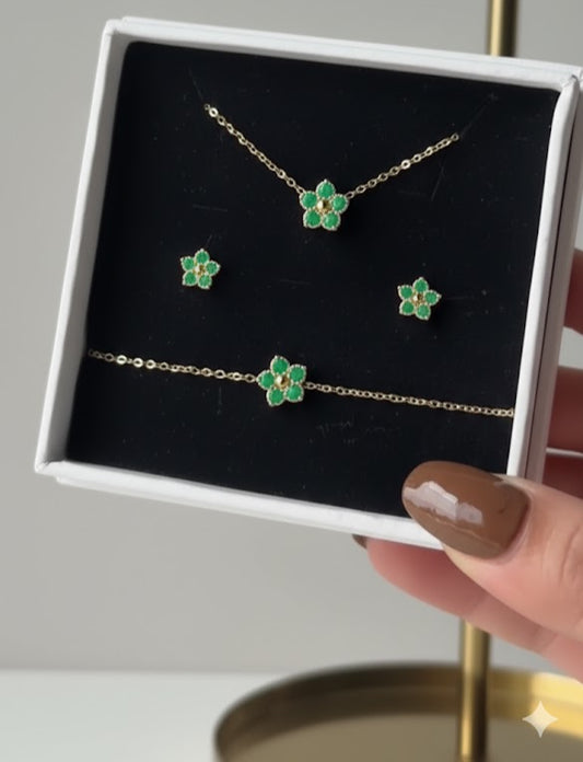 Jewelry set with green flower-shaped pendants in a box, held by a hand.